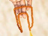 Nepali Rudraksha Mala held in hand showing 5 Mukhi beads and yellow tassel