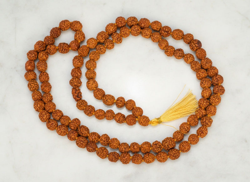 Nepali Rudraksha Mala - 108 Beads 1 Original 5 Mukhi Rudraksha Mala 108+1 beads with golden tassel laid on marble surface