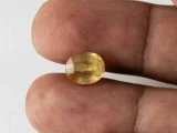 Holding a certified 4.96 ratti yellow sapphire from Ratna Gems