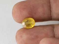 Holding a certified 5.02 ratti yellow sapphire from Ratna Gems