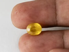 Holding a certified 5.12 ratti yellow sapphire from Ratna Gems