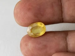 Holding a certified 5.36 ratti yellow sapphire from Ratna Gems