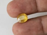 Holding a certified 5.38 ratti yellow sapphire from Ratna Gems