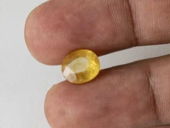 Holding a certified 5.38 ratti yellow sapphire from Ratna Gems