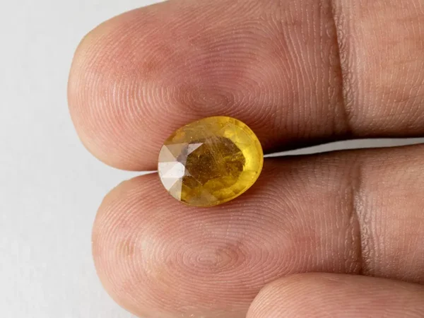 Holding a certified 6.02 ratti yellow sapphire from Ratna Gems