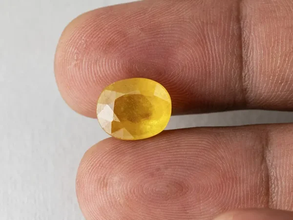 Holding a certified 6.18 ratti yellow sapphire from Ratna Gems