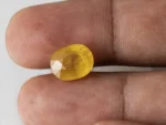 Holding a certified 7.29 ratti yellow sapphire from Ratna Gems