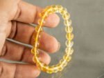 Hand holding natural yellow citrine bracelet showing transparency and bead size
