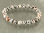 Top view of grey jasper healing crystal bracelet on grey background