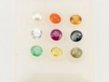 9 loose Navratna gemstones on white background - Ruby, Pearl, Emerald, Pukhraj, Neelam, Gomed, Lehsunia, Moonga, American Diamond