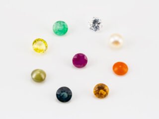 Natural Navratna Stone Set with 9 gemstones including Ruby, Pearl, Emerald, Yellow Sapphire, Blue Sapphire, Hessonite, Cat's Eye, Red Coral and American Diamond arranged in white tray