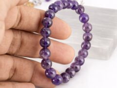 Amethyst bracelet held in hand showing bead size and color