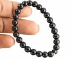 Black Obsidian bracelet held in hand showing bead size and finish