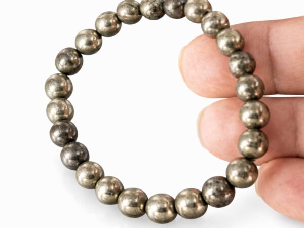 Fingers holding a genuine natural Pyrite gemstone bracelet vertically, showcasing the 8mm golden beads.