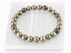 Authentic metallic golden Pyrite stone bracelet resting on a white rectangular display plate.