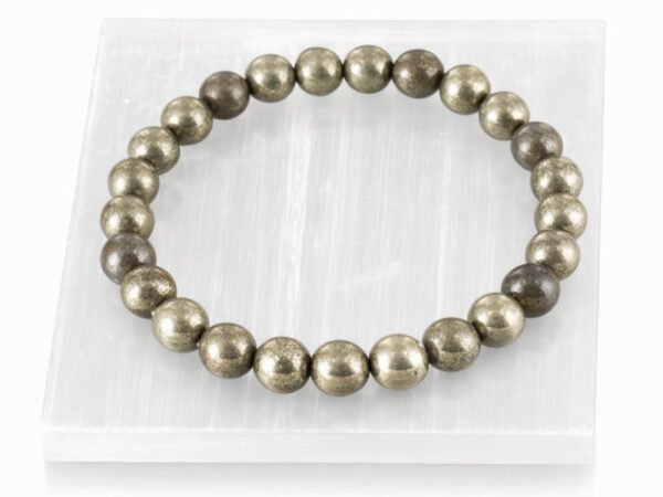 Authentic metallic golden Pyrite stone bracelet resting on a white rectangular display plate.