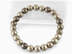 Close-up of an authentic metallic golden Pyrite stone bracelet resting on a white textured display plate.