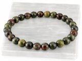 Authentic natural Red Bloodstone gemstone bracelet resting flat on a white textured display plate.