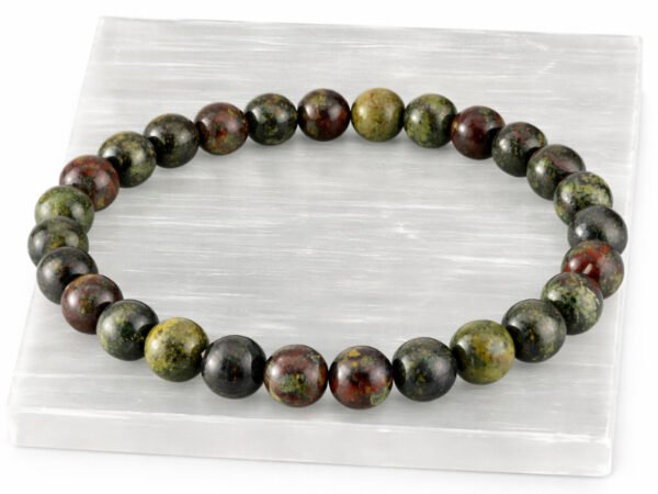 Authentic natural Red Bloodstone gemstone bracelet resting flat on a white textured display plate.