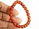 Hand holding a genuine natural Red Quartz gemstone bracelet, showcasing the 8mm beads and their bright translucent red color.