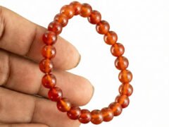 Hand holding a genuine natural Red Quartz gemstone bracelet, showcasing the 8mm beads and their bright translucent red color.