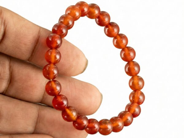 Hand holding a genuine natural Red Quartz gemstone bracelet, showcasing the 8mm beads and their bright translucent red color.