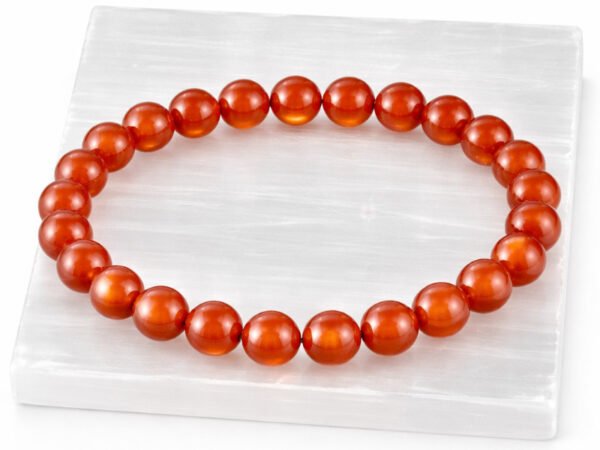 Authentic natural Red Quartz gemstone bracelet resting flat on a white textured display plate.