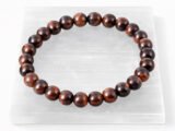 Authentic natural Red Tiger Eye gemstone bracelet resting flat on a white textured display plate.