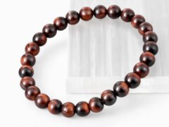 Close-up of an authentic natural Red Tiger Eye stone bracelet resting on a white rectangular display plate.