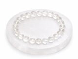 Authentic natural Rock Crystal Sphatik gemstone bracelet resting flat on a round white display plate.