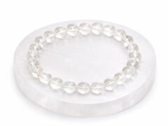 Authentic natural Rock Crystal Sphatik gemstone bracelet resting flat on a round white display plate.