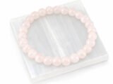 Authentic natural Rose Quartz gemstone bracelet resting flat on a square white textured display plate.