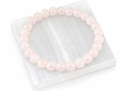 Authentic natural Rose Quartz gemstone bracelet resting flat on a square white textured display plate.