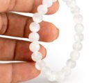 Hand holding a genuine natural Selenite gemstone bracelet, showcasing the 8mm beads and their pure colorless luminosity.