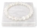 Authentic natural Selenite gemstone bracelet resting flat on a white square display plate.
