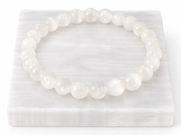 Authentic natural Selenite gemstone bracelet resting flat on a white square display plate.