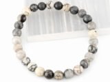 Authentic natural Spider Web Agate gemstone bracelet resting flat on a white square display plate.