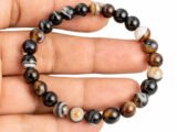 Hand holding a genuine natural Sulemani Hakik Black Agate gemstone bracelet flat across the palm, showcasing the banded 8mm beads.