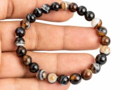 Hand holding a genuine natural Sulemani Hakik Black Agate gemstone bracelet flat across the palm, showcasing the banded 8mm beads.