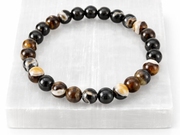 Authentic natural Sulemani Hakik gemstone bracelet resting flat on a white textured square display plate.