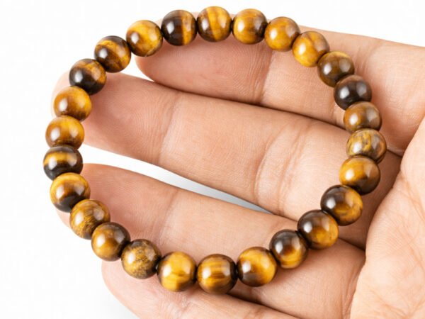 Hand holding a genuine natural Tiger Eye gemstone bracelet flat across the palm, showcasing the golden-yellow banded 8mm beads.