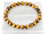 Authentic natural Tiger Eye gemstone bracelet resting flat on a white square display plate.