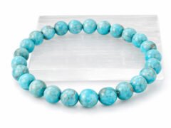Authentic Turquoise Firoza gemstone bracelet resting flat on a white square display plate.