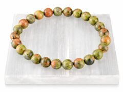 Authentic natural Unakite gemstone bracelet resting flat on a white square textured display plate.