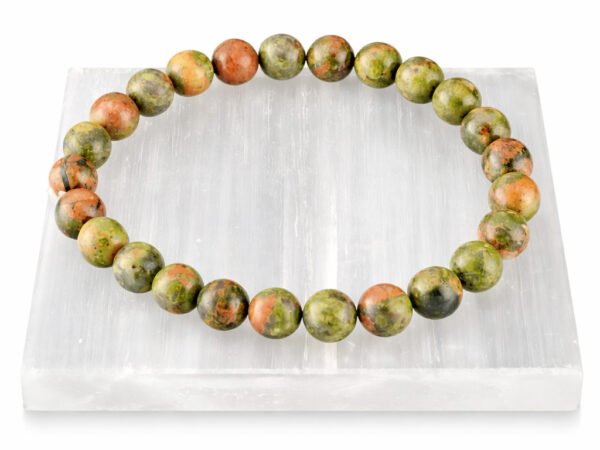 Authentic natural Unakite gemstone bracelet resting flat on a white square textured display plate.