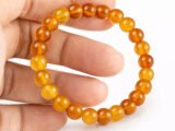 Hand holding a genuine natural Yamini Hakik Yellow Agate gemstone bracelet, showcasing the warm honey-colored 8mm beads.