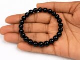 Hand holding a genuine natural Black Quartz gemstone bracelet flat across the palm, showcasing the glossy 8mm beads.