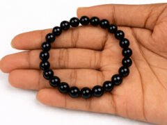 Hand holding a genuine natural Black Quartz gemstone bracelet flat across the palm, showcasing the glossy 8mm beads.