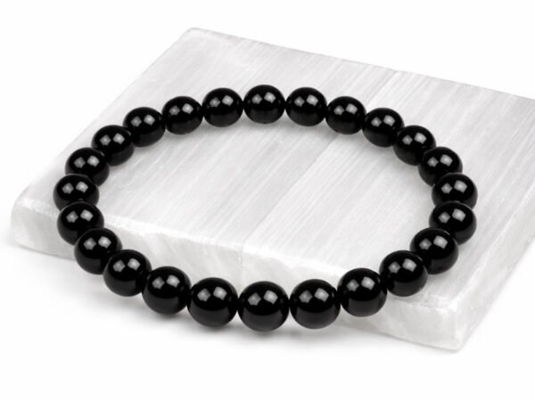 Authentic natural Black Quartz gemstone bracelet resting flat on a white square textured display plate.